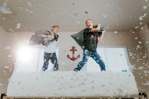 Two kids pillow fighting on a bed