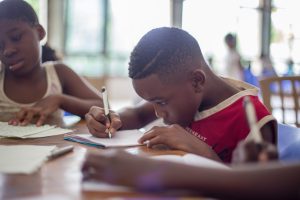 A student writing on a brown table