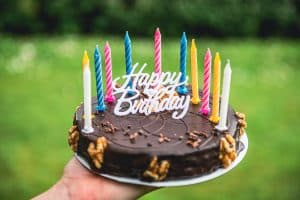 Chocolate birthday cake against grassy background.