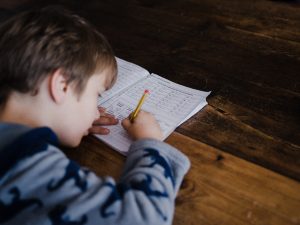 Student taking a test on a wooden table.